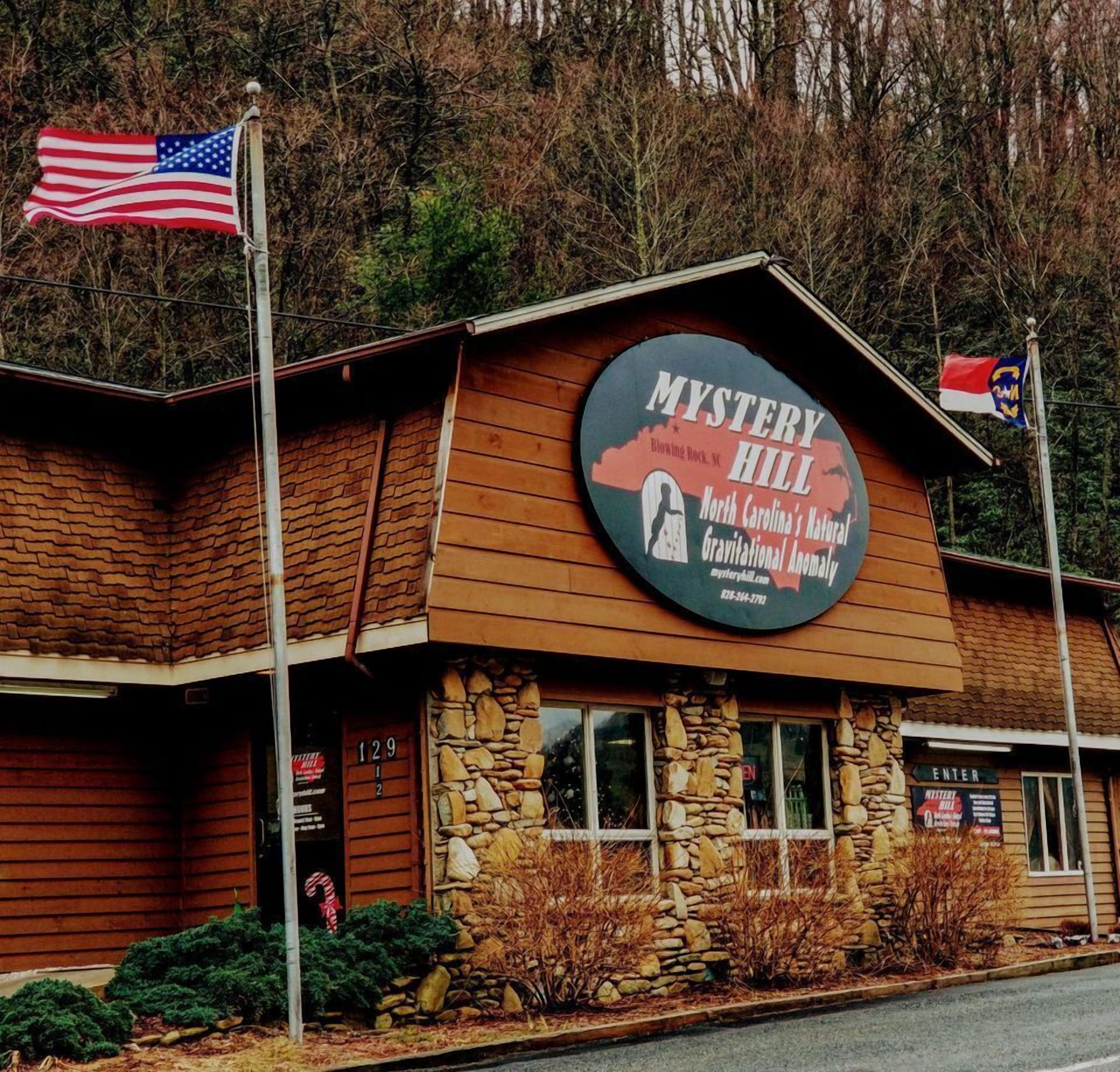 A building with a sign reading "Mystery Hill" and an American flag.