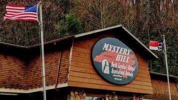 Un edificio con un letrero que dice "Mystery Hill" y una bandera estadounidense.