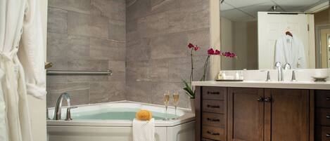A modern bathroom with a bathtub, a vanity with a mirror, and a shower area.