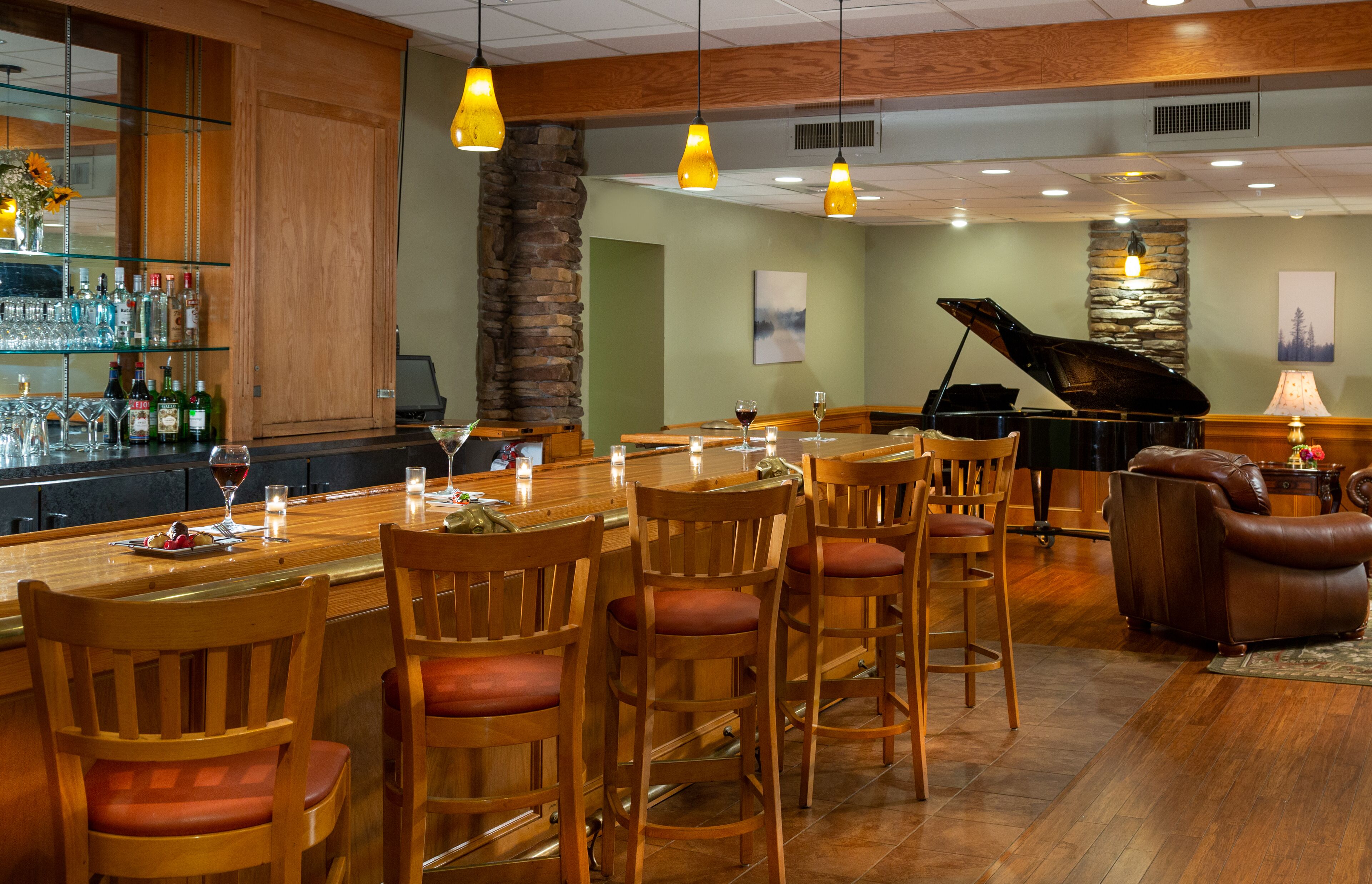 A bar area with wooden chairs, a piano, and a stone pillar.