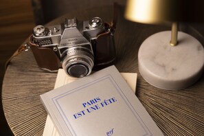 A vintage Kodak camera, a book titled "PARIS EST UNE FÊTE", and a lamp on a textured table. - Hotel Le Rocroy (Paris)