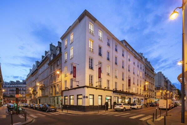 A multi-story hotel with a classic European architectural style, featuring a ground floor with large windows and a visible entrance. - Hotel Le Rocroy (Paris)