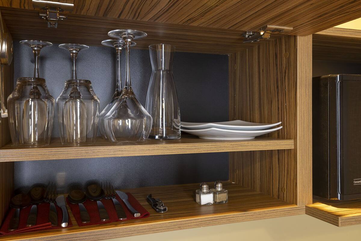 A wooden cabinet with glassware and cutlery.