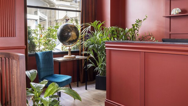Ein Zimmer mit blauem Sessel, Globus auf einem Tisch und diversen Pflanzen.