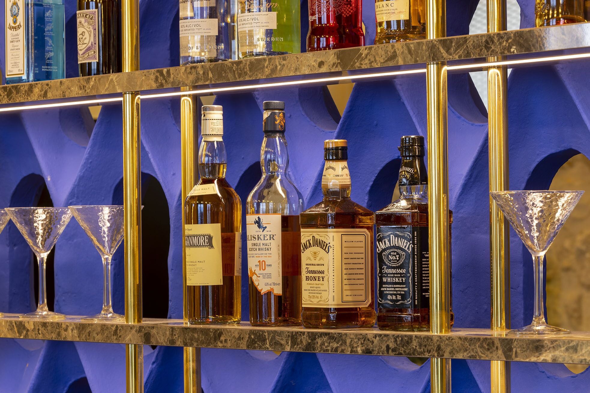 A bar with various bottles of alcohol and two martini glasses.