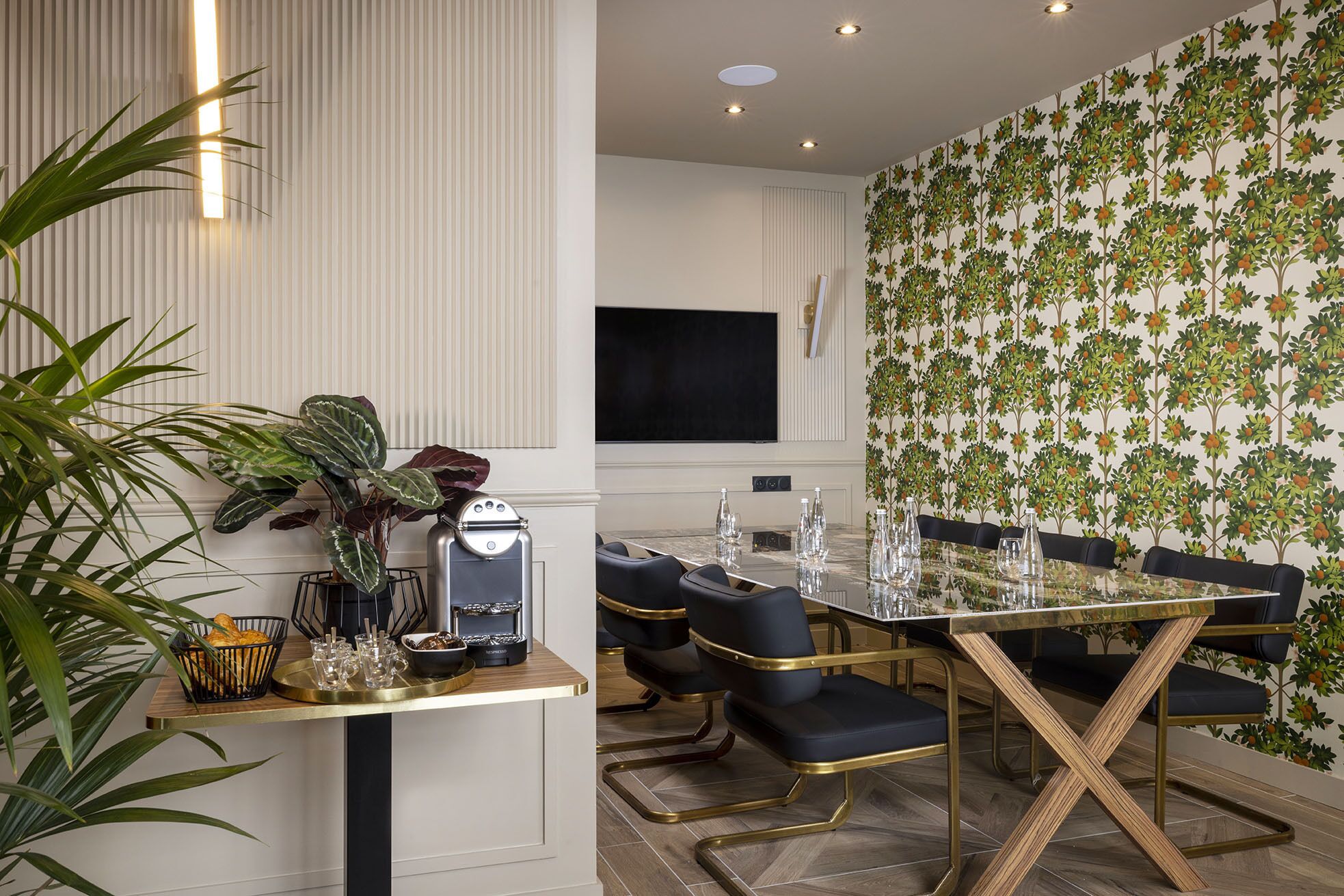 A modern dining area with a long table, black chairs, and a coffee machine.