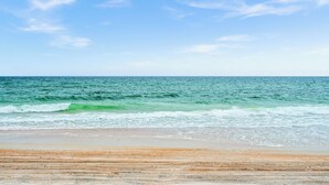 A beach with waves and a clear sky.