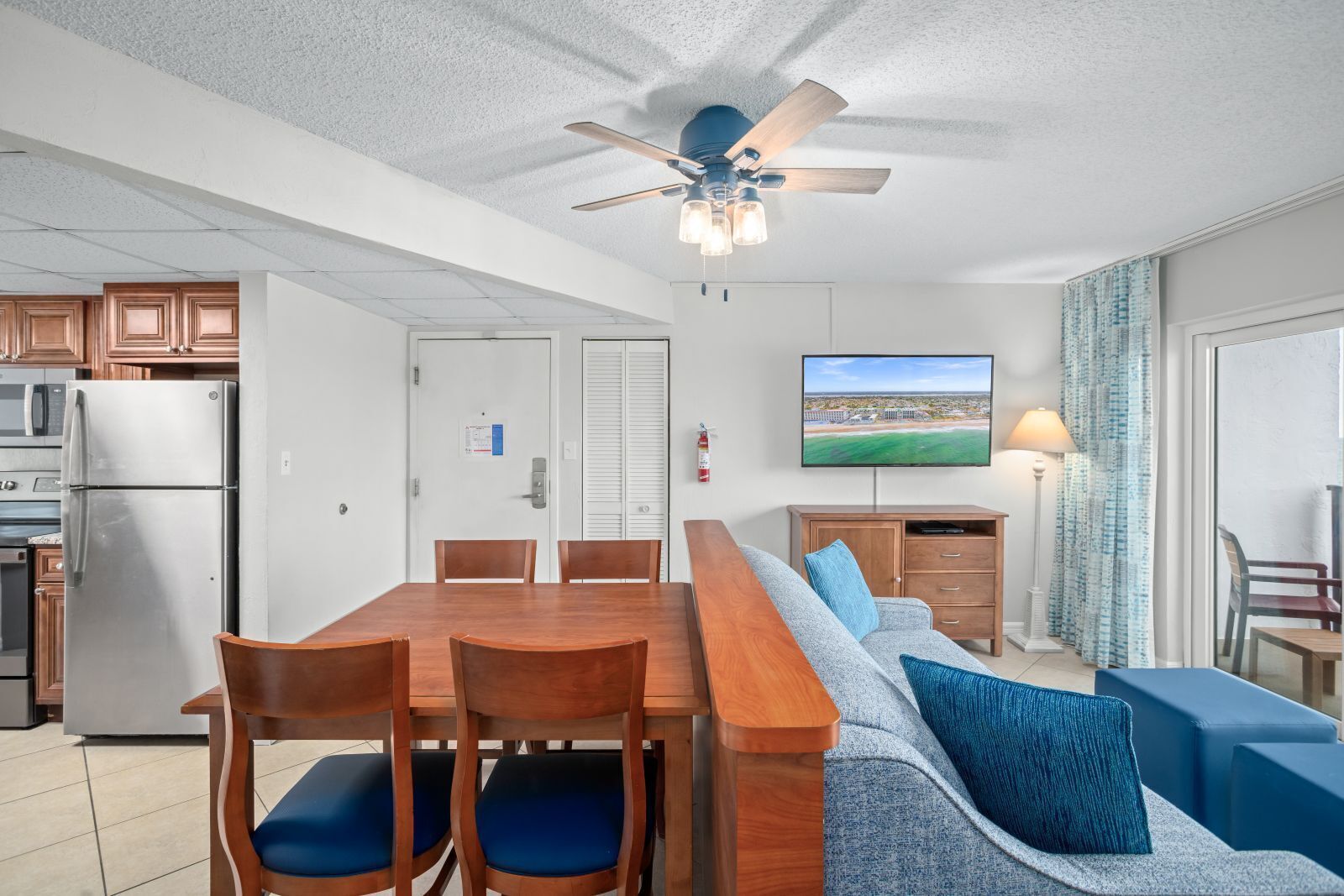 A modern kitchen with a built-in microwave, refrigerator, and a ceiling fan.