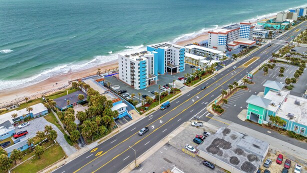 Paisaje costero con playa, edificios altos y una carretera con vehículos.