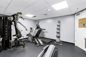A gym with exercise machines, a treadmill, and a wall-mounted medicine ball rack. - Tropic Sun Towers (Ormond Beach)