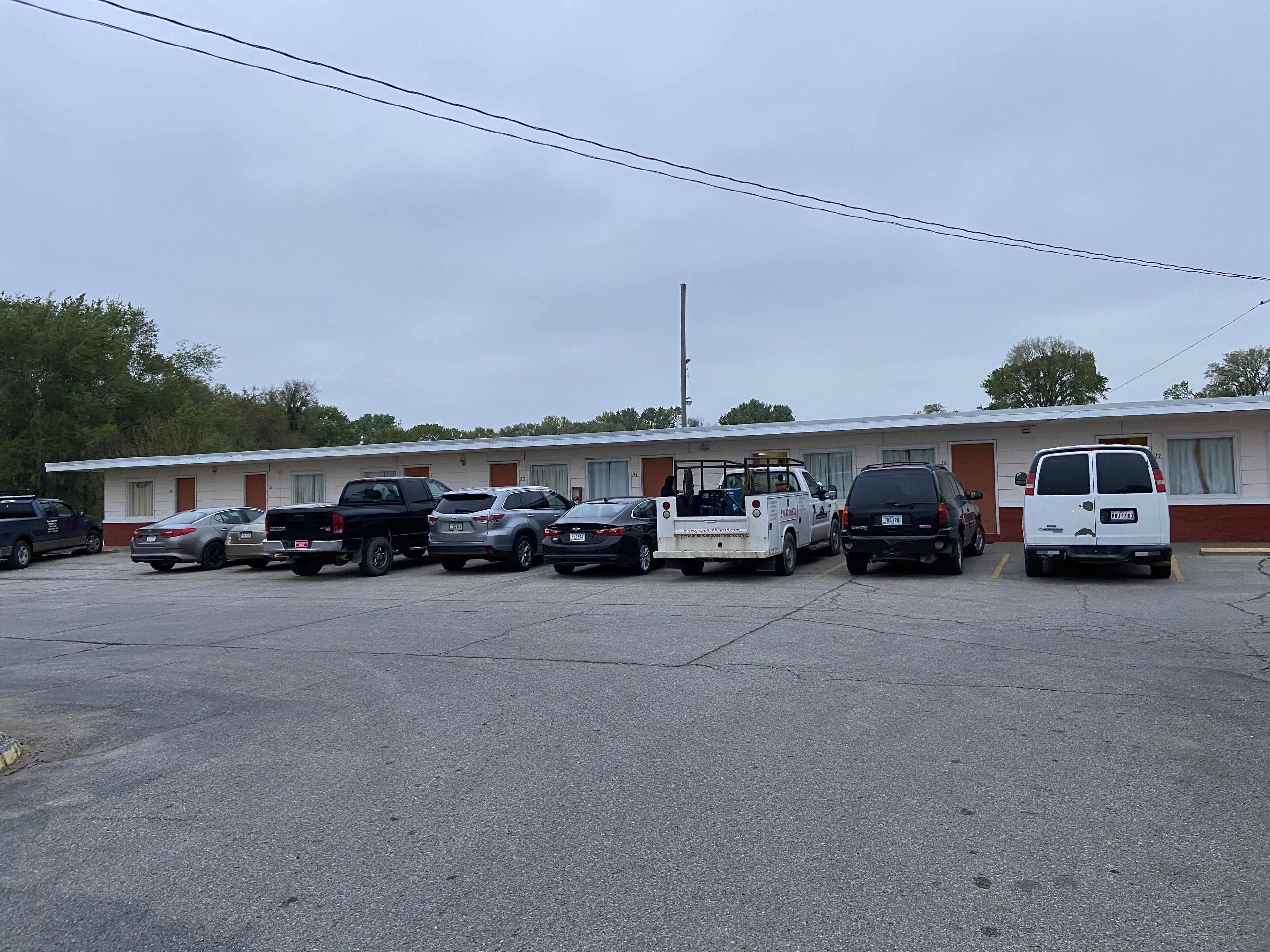 A motel with a row of parked cars and a white van in front.