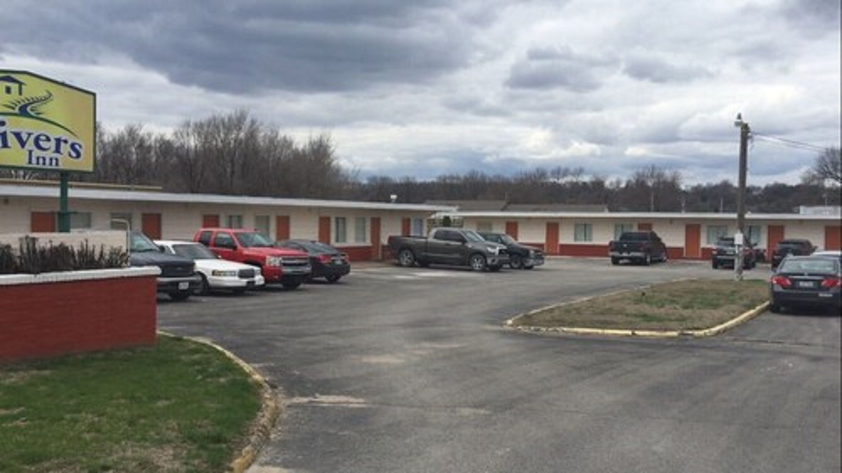 A Rivers Inn motel with a parking lot and several parked cars.