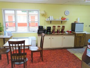 A small kitchen with a dining area, a microwave, a coffee maker, and a refrigerator.