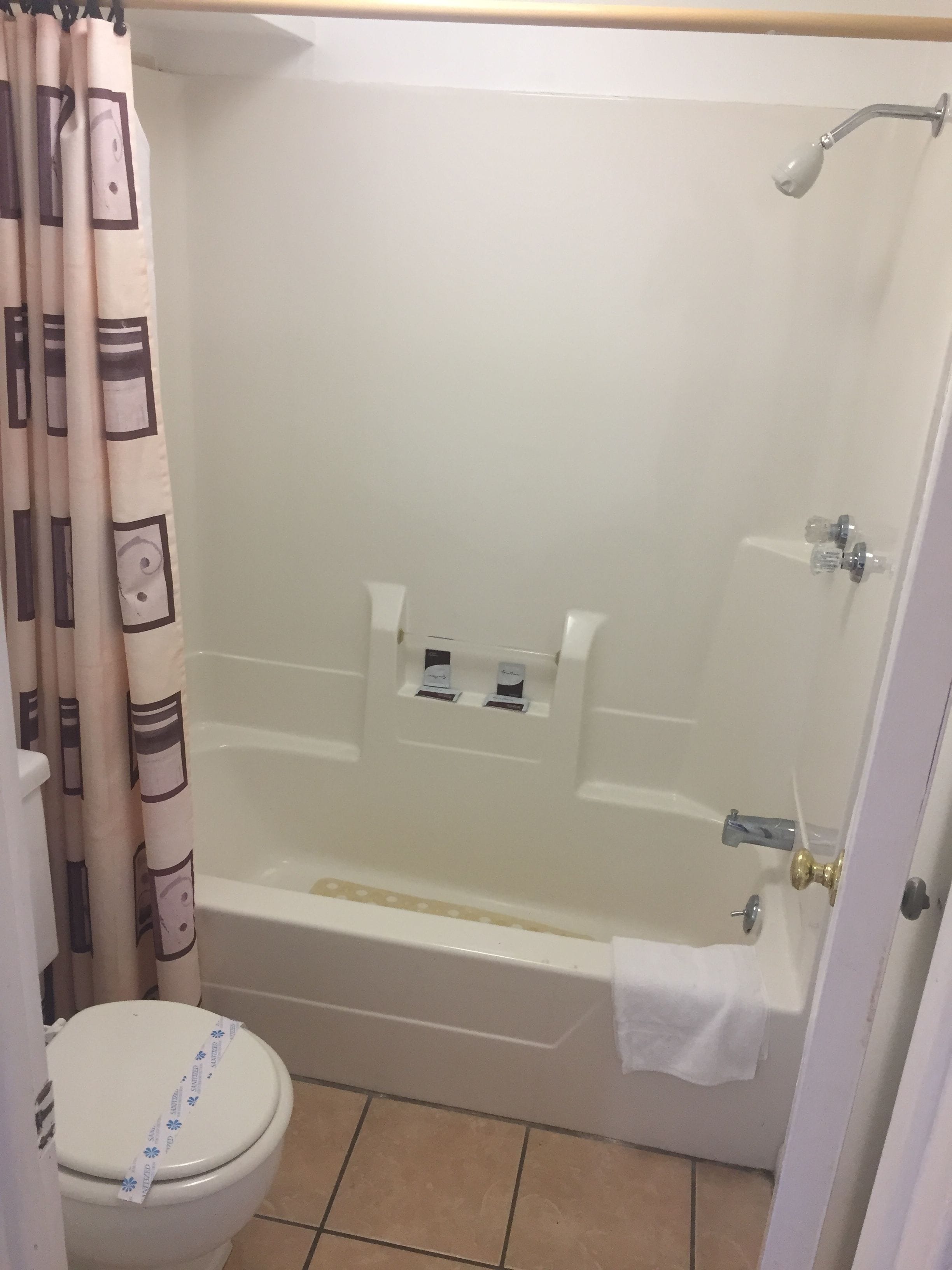 A bathroom with a bathtub, toilet, and shower curtain.