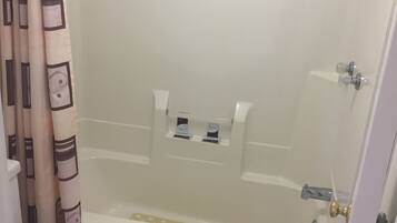 A bathroom with a bathtub, toilet, and shower curtain.