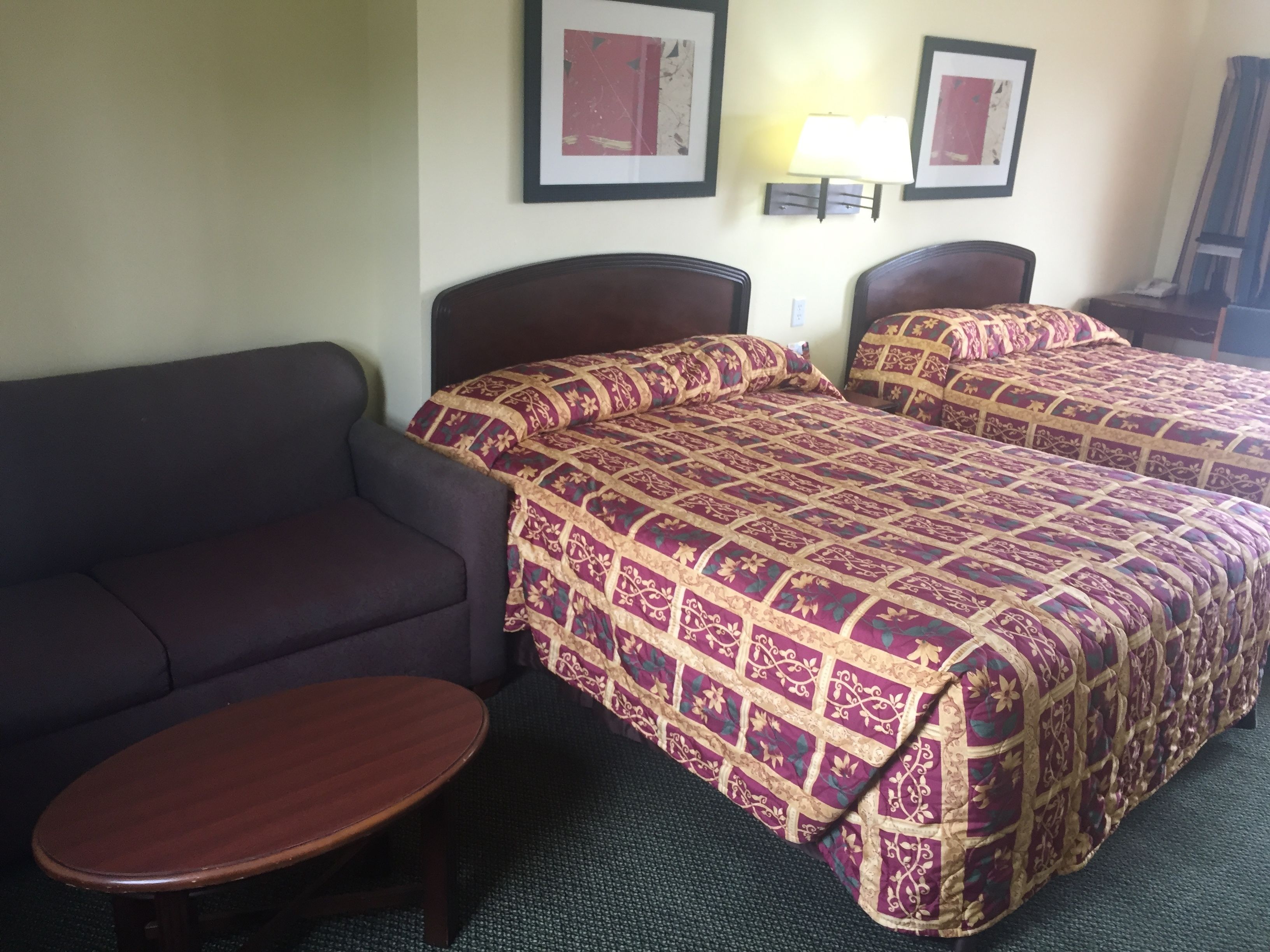 Habitación de hotel con dos camas, un sofá y una pequeña mesa.