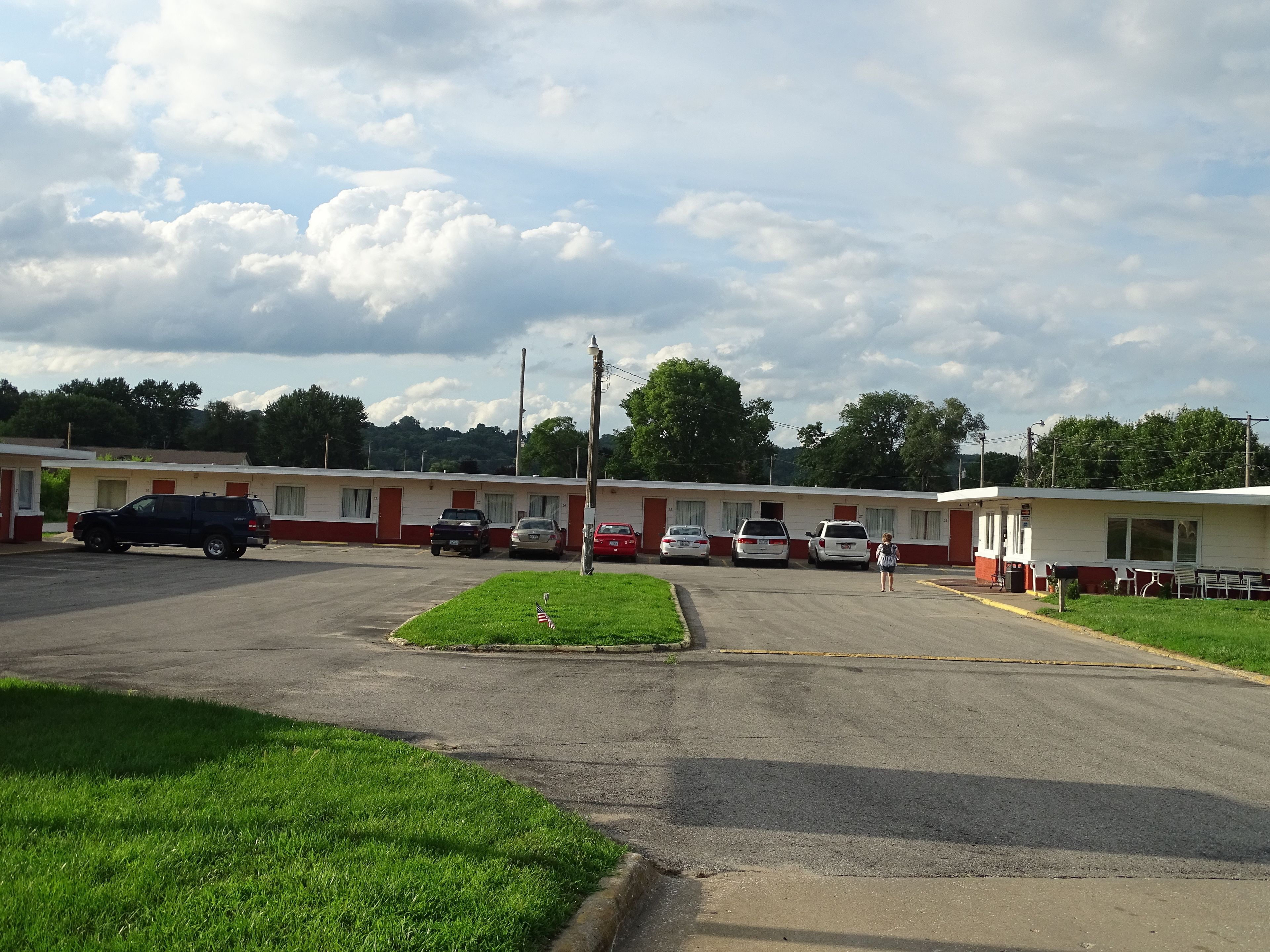 A motel with multiple rooms, a parking lot, and a grassy area.