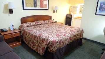 A hotel room with a bed, a nightstand with a lamp, a telephone, and a framed picture on the wall.