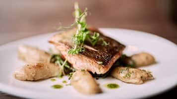 A plate with a piece of salmon, potatoes, and a garnish.