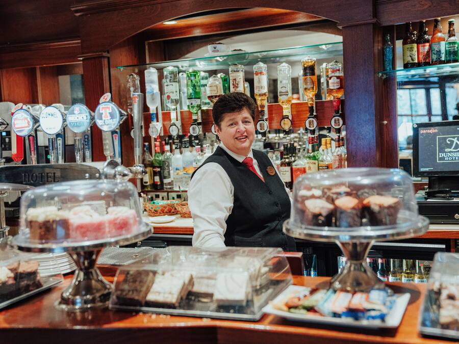 A bar area with multiple liquor taps, a display of various bottles, and a counter with desserts.