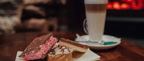A dessert tray with two pieces of cake and a cup of coffee on a wooden table.