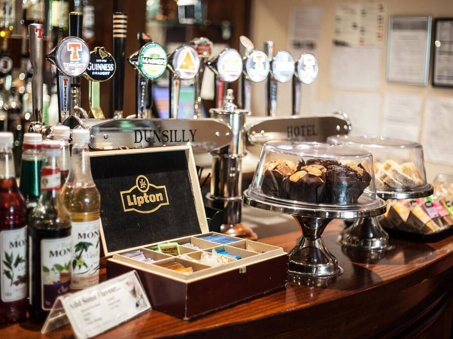 Una zona de bar con diversas botellas de licores, una selección de cervezas de barril y una exhibición de pasteles y bombones.