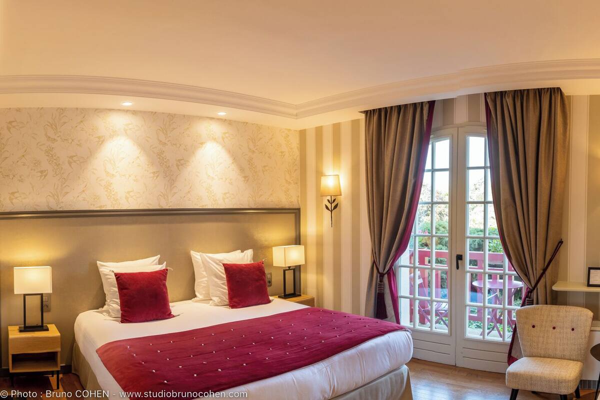 Een hotelkamer met een groot bed, twee bedlampen, een stoel, een klein tafeltje en een televisie.