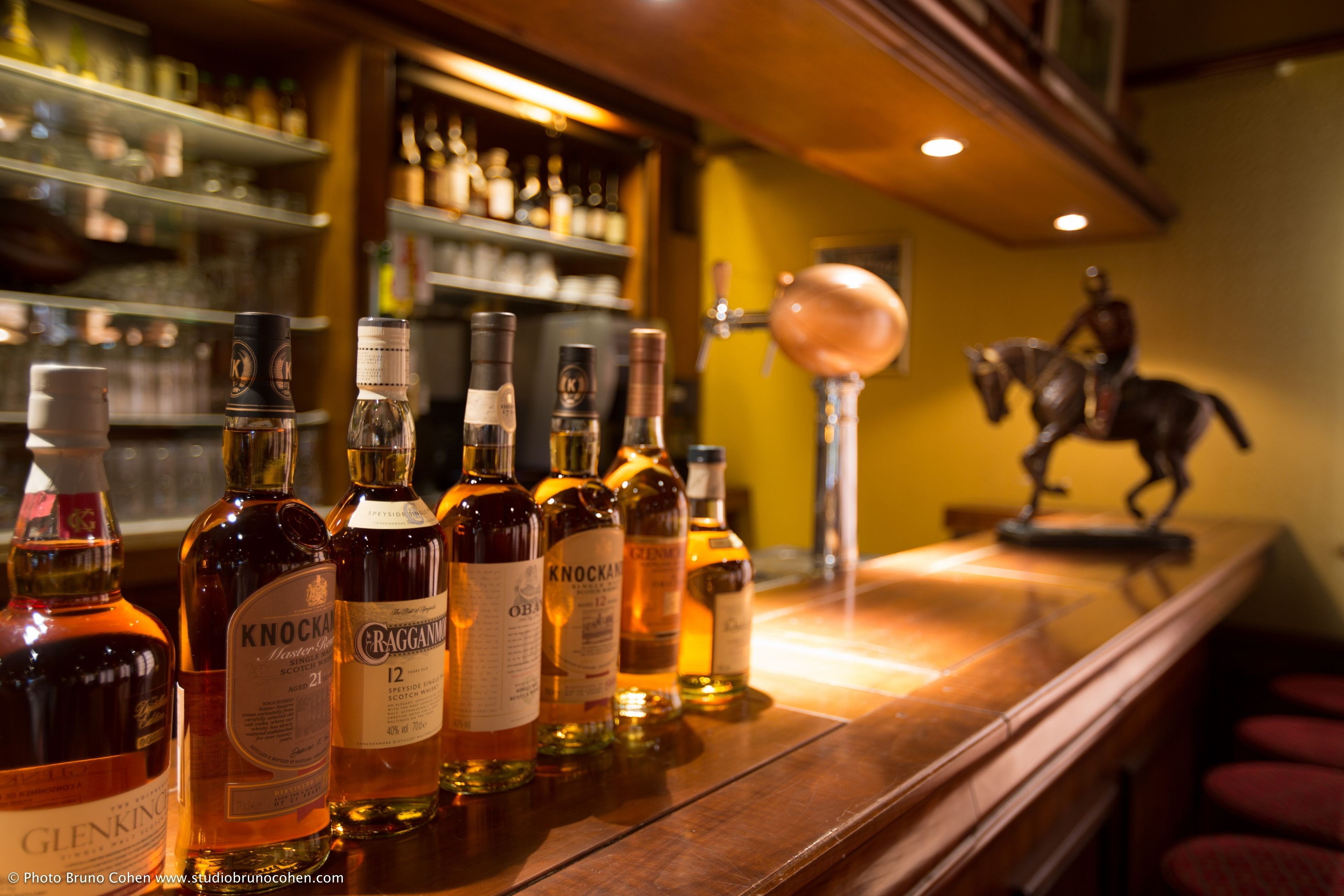 Un bar con varias botellas de licor y un grifo de cobre.