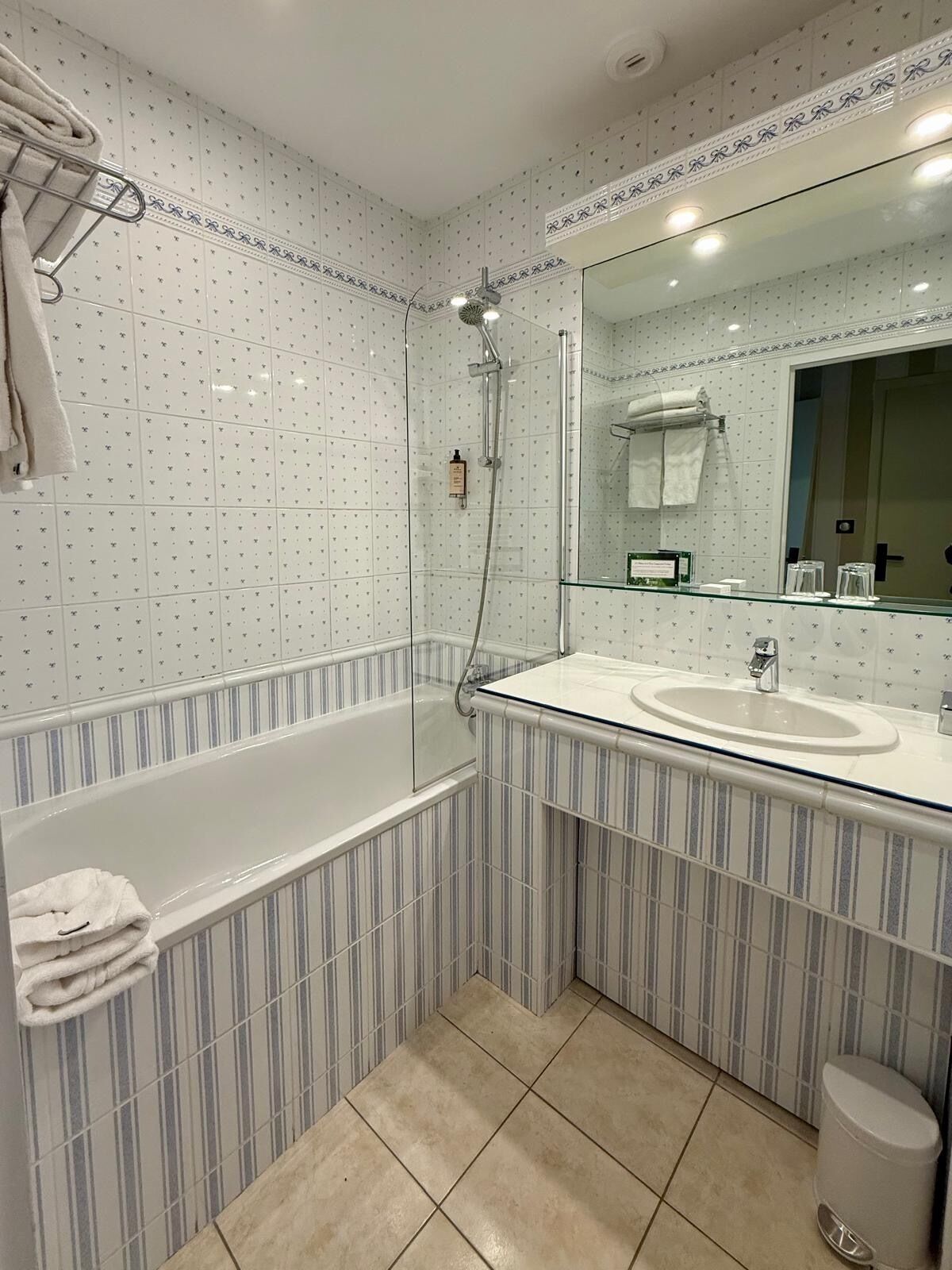 Een badkamer met een douche met glazen wanden, een grote spiegel en een gestreept aanrichtmeubel.