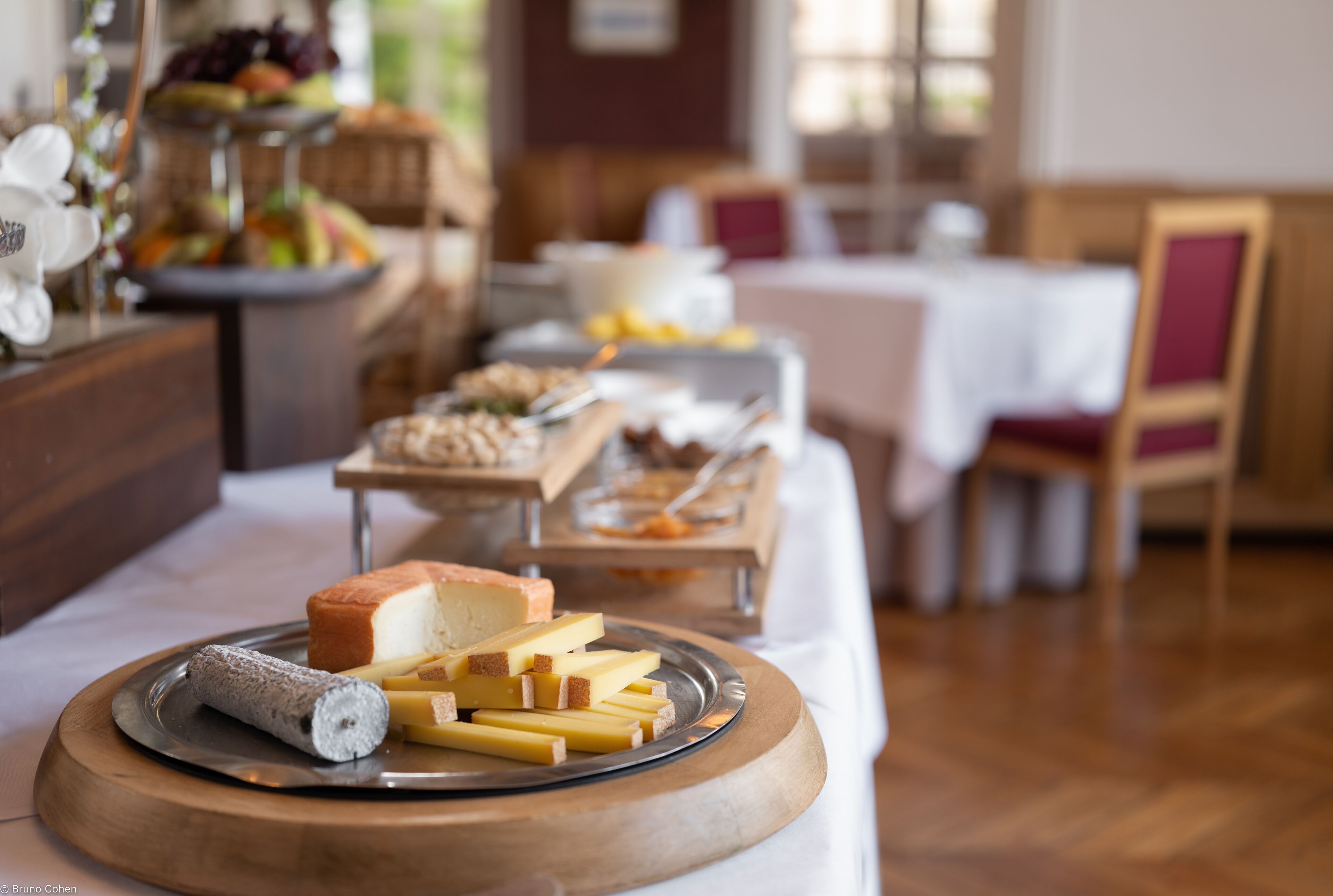 A buffet table with various cheeses and bread.