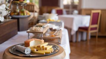 A buffet table with various cheeses and bread.