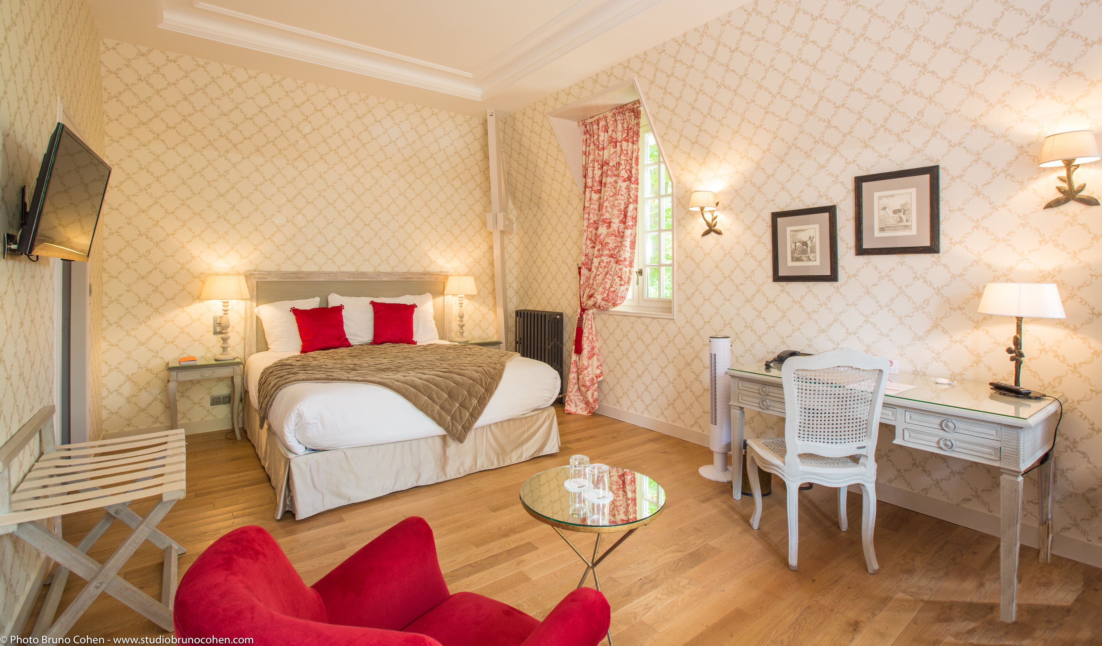 Une chambre d’hôtel avec un lit, un bureau, une chaise et une petite table.
