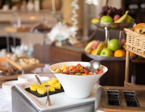 Ein reichhaltiges Buffet mit verschiedenen Früchten und einer Schüssel gemischtem Obstsalat.