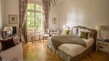 Ein helles Schlafzimmer mit einem großen Bett, einem Schreibtisch, einem Stuhl und einem Fernseher.