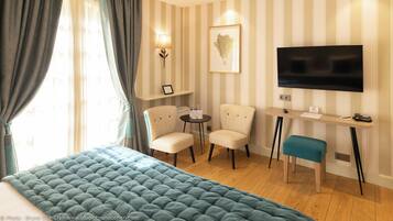 Habitación de hotel con una cama grande, un escritorio con televisor, dos sillones y una mesita.