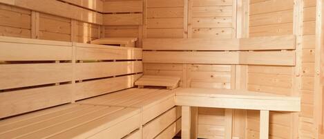 A wooden sauna with benches and a bench seat, featuring a sloped ceiling and wooden walls.