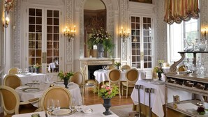 A formal dining room with ornate decor, multiple tables set for dining, and a fireplace. - Chateau Colbert (Maulevrier)