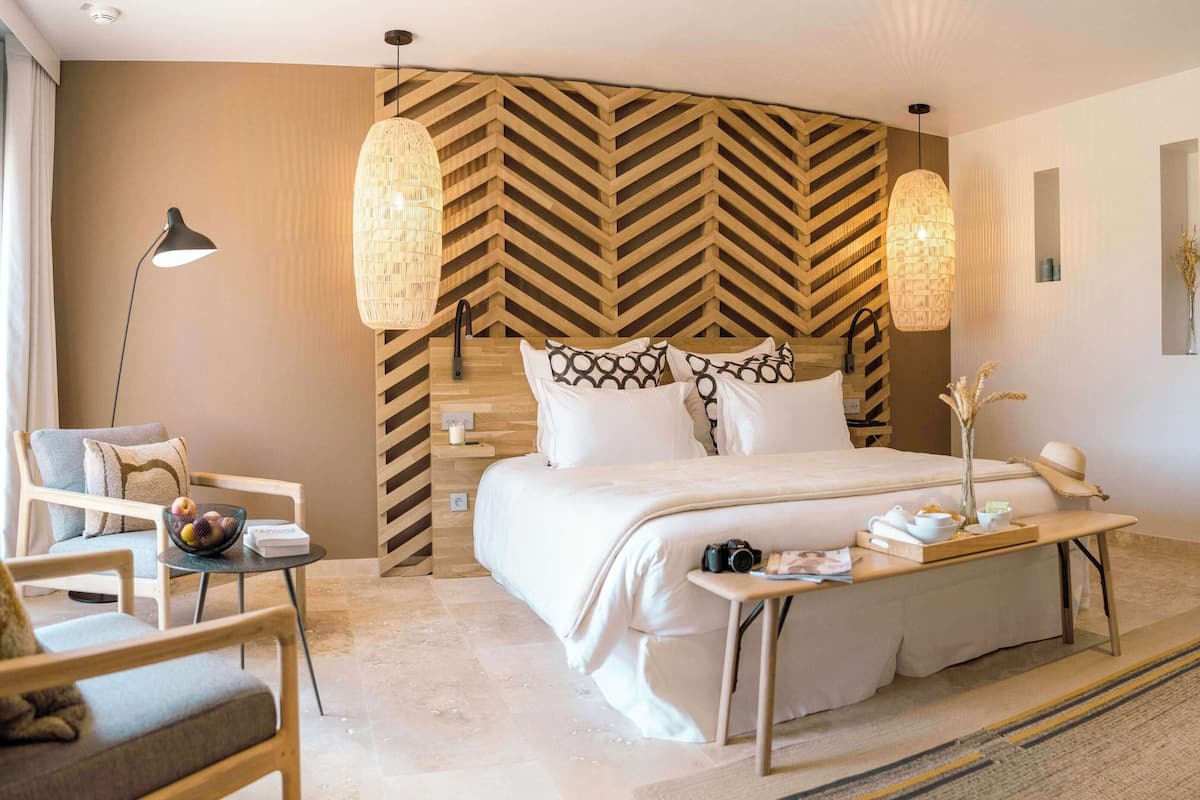 Ein modernes Hotelzimmer mit einem großen Bett, einem Schreibtisch, einem Stuhl und einem Spiegel.