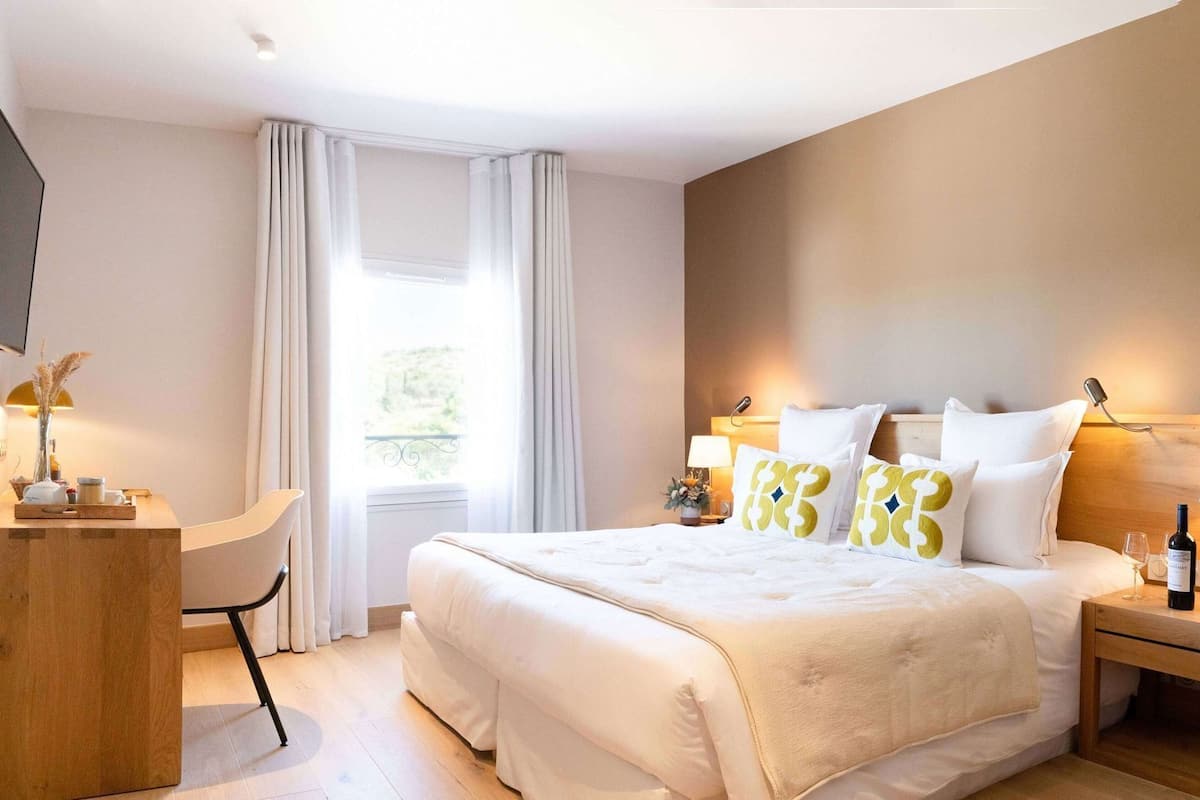 Ein Hotelzimmer mit Bett, Nachttischen, Schreibtisch, Stuhl und Fernseher.