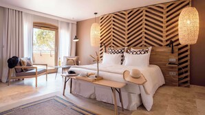 Ein modernes Schlafzimmer mit einem großen Bett, einem hölzernen Kopfteil, einer Sitzbank und Blick ins Freie.