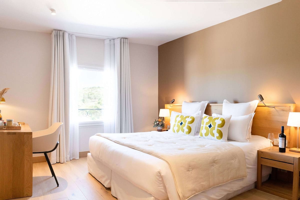 Ein Hotelzimmer mit Bett, Nachttischen, Schreibtisch, Stuhl und Fernseher.