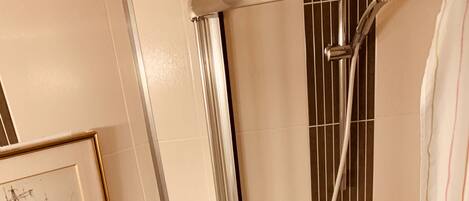 Un baño con ducha, inodoro y un cuadro en la pared.
