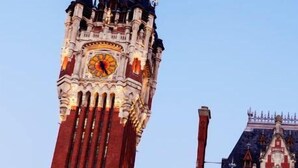 Um edifício histórico com uma torre do relógio imponente e uma grande entrada em arco.