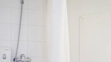 Une salle de bain avec une douche, des toilettes et un mur recouvert de carreaux blancs.
