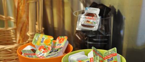 Dos recipientes con alimentos, uno naranja y uno verde, sobre una superficie con una cesta de mimbre y un electrodoméstico de acero inoxidable al fondo.