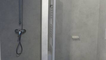 A bathroom with a shower, toilet, and a towel rack.