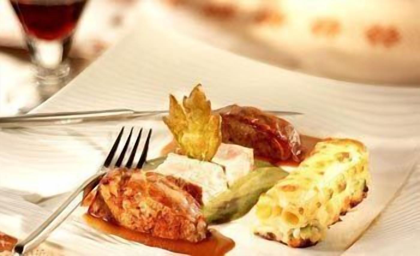 A plate of food with a fork and a glass of red beverage.
