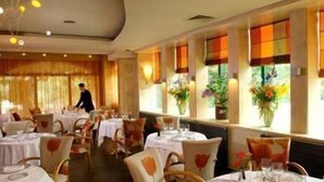 Un restaurante con mesas redondas, sillas y un camarero.