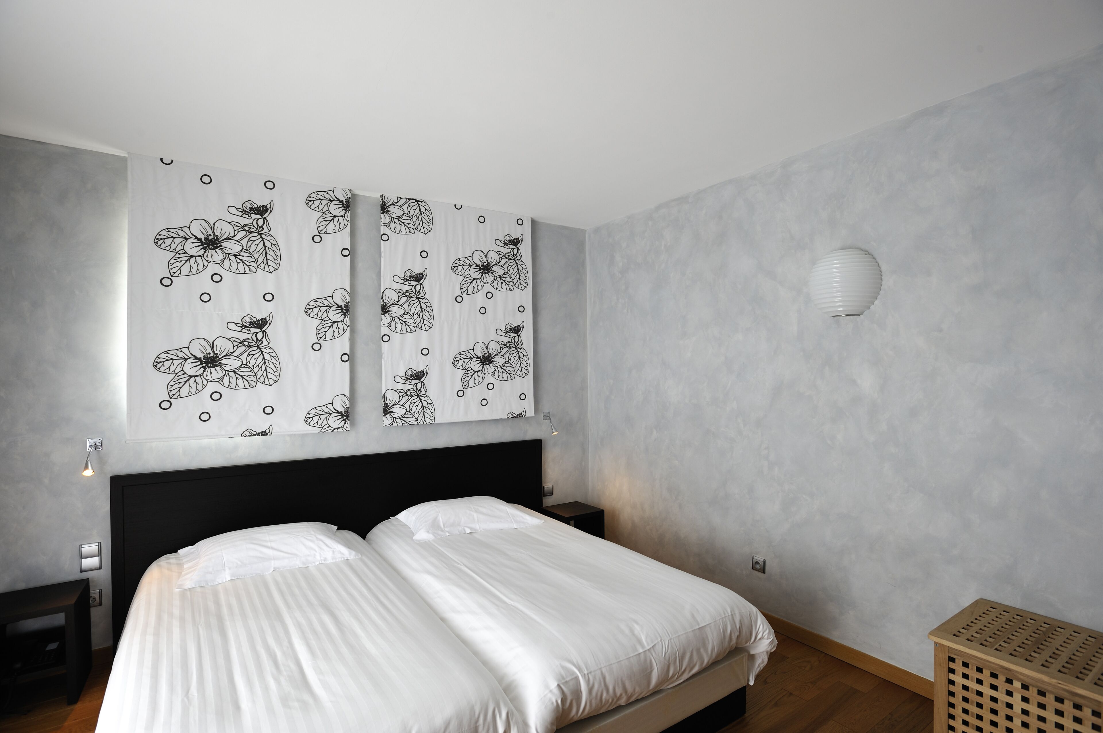 Ein modernes Schlafzimmer mit einem großen Bett, einem Nachttisch, einer Wandlampe und einem Wäschekorb.