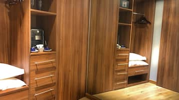 A walk-in closet with multiple wooden drawers and shelves, a mirror, and a small table with a lamp.